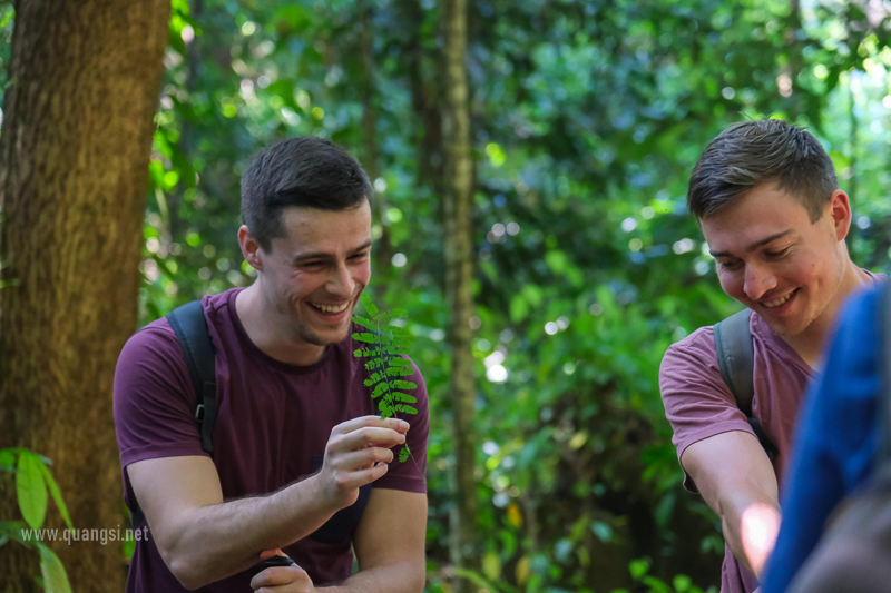 two men smiling and holding a leaf