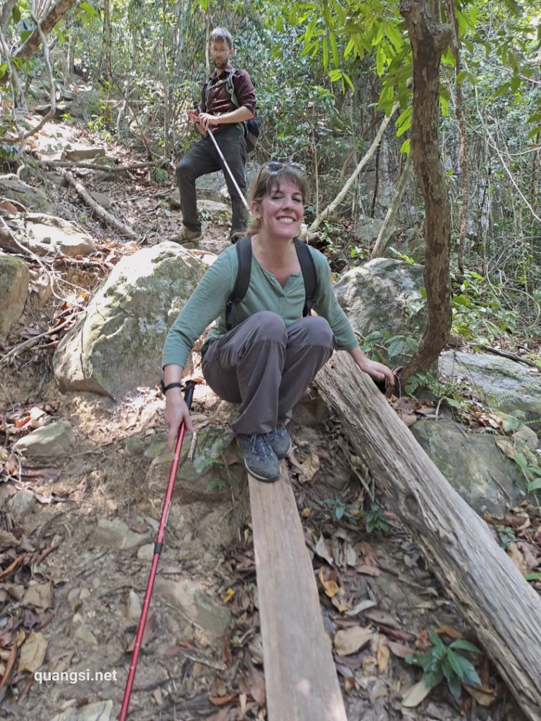 a woman sitting on a log with a man on a rope