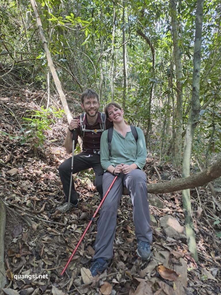 a man and woman sitting on a tree branch in the woods