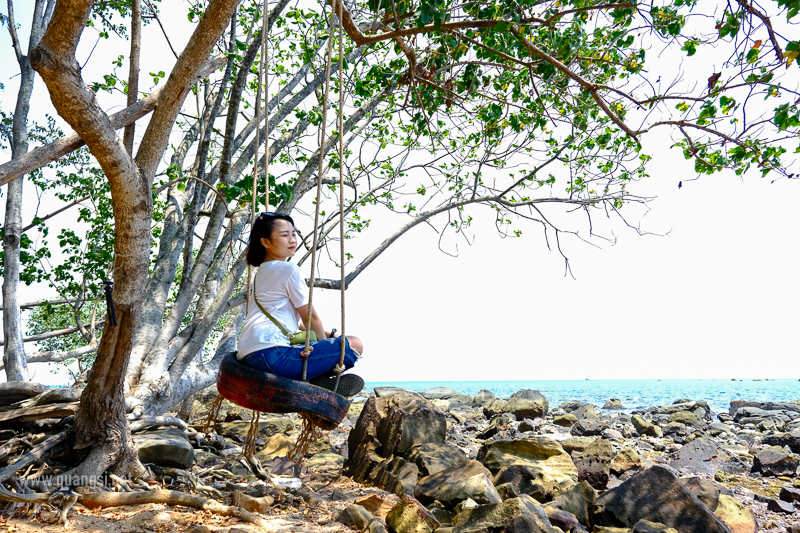 a woman sitting on a swing under a tree