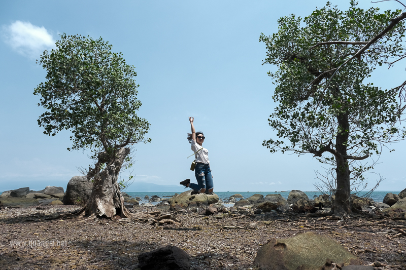 a woman standing on rocks with arms up in air at Hon Mot